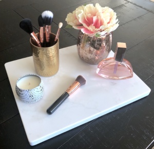 cheese board with makeup brushes, flowers and candle
